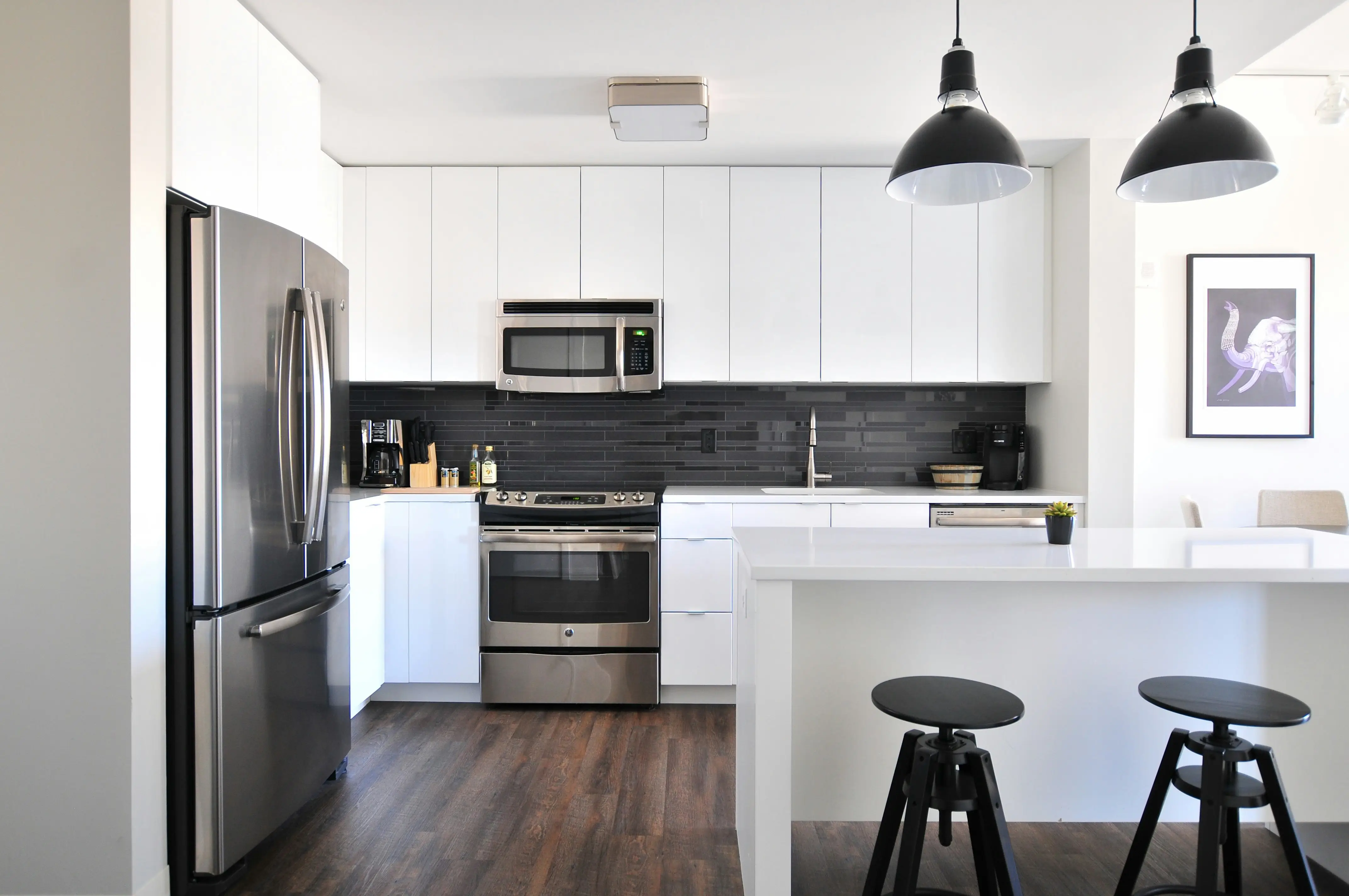 Cocina moderna en Chile con gabinetes blancos, electrodomésticos de acero inoxidable y diseño minimalista con isla central